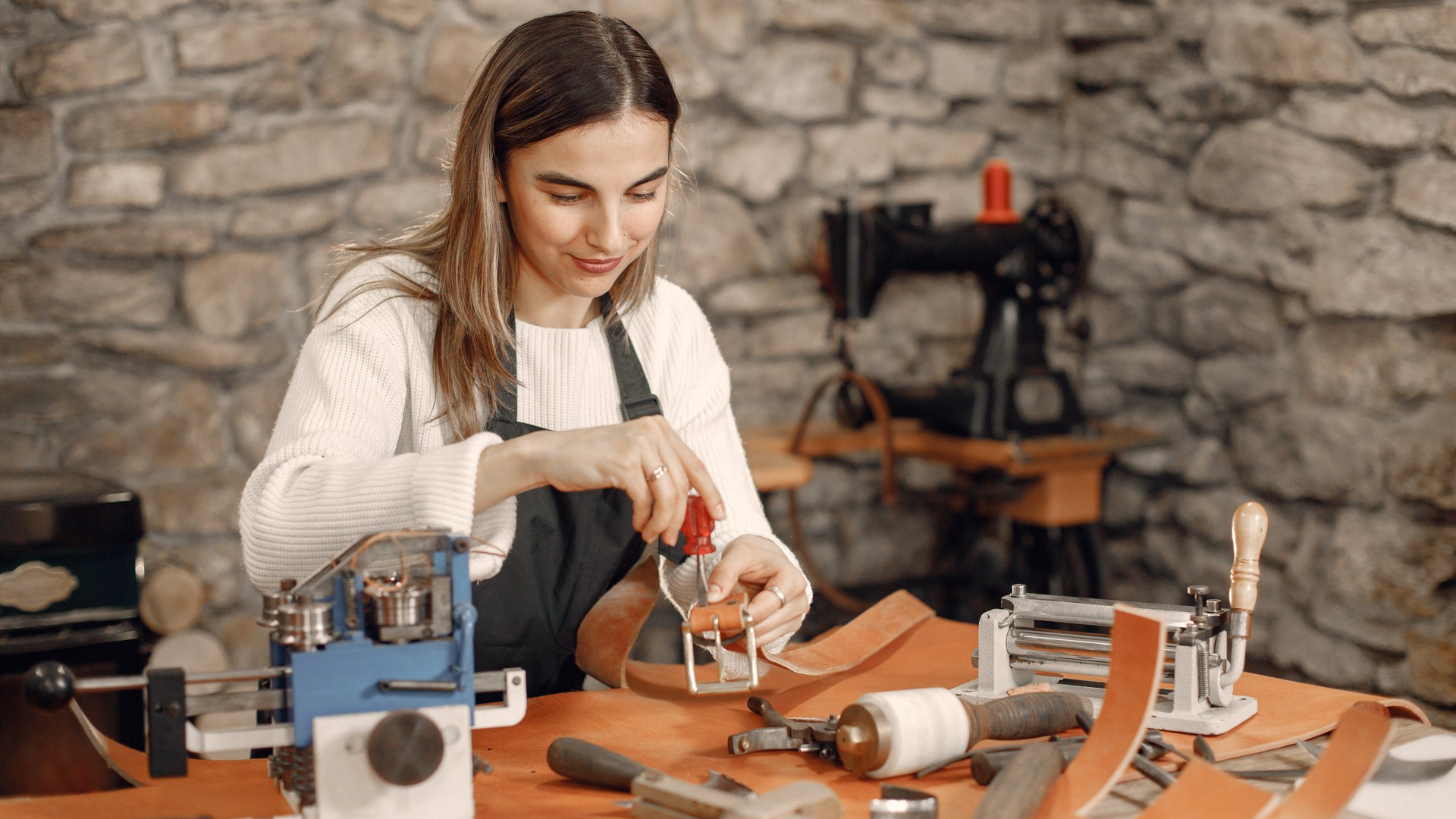 Lederhandwerkerin arbeitet in einer Werkstatt an einem Gürtel